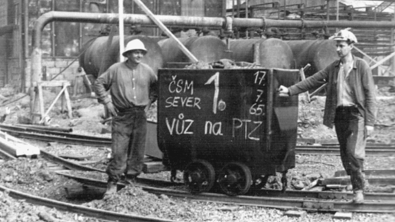 dwaj górnicy stojący przy wózku z węglem