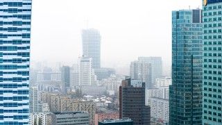 Widok na wieżowce Warszawy w mglisty poranek, miasto jest pokryte smogiem