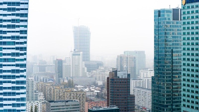 Widok na wieżowce Warszawy w mglisty poranek, miasto jest pokryte smogiem
