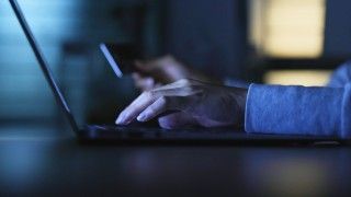 Dłonie na klawiaturze na ciemnym tle.