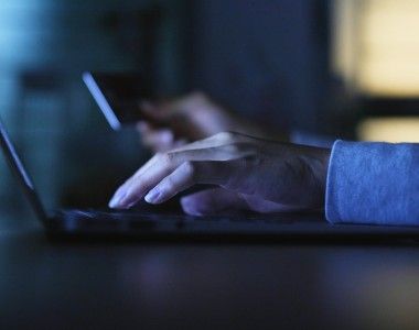 Dłonie na klawiaturze na ciemnym tle.