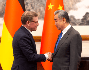 Mężczyźni ściskają sobie ręce, w tle flagi Niemiec i Chin