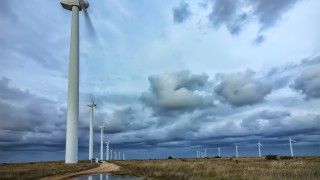turbiny wiatrowe na silnym wietrze, śmigła obracają się tak szybko że są zamazane, na ziemi są kałuże po burzy