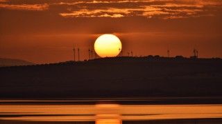 zachód słońca nad pagórkiem z turbinami wiatrowymi