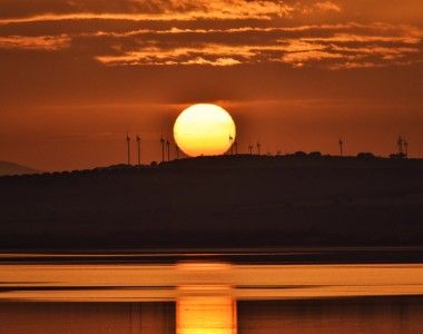 zachód słońca nad pagórkiem z turbinami wiatrowymi