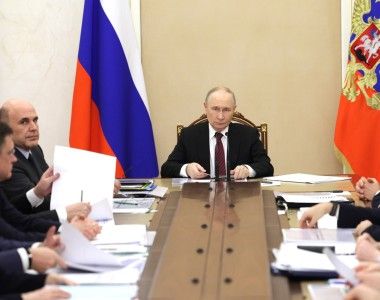 Władimir Putin siedzący przy długim stole na spotkaniu w sprawie gospodarki Rosji.