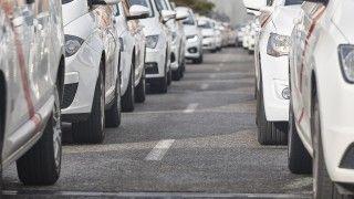 Białe samochody stojące na jezdni.