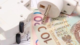 Wtyczka elektryczna leżąca na polskich banknotach.