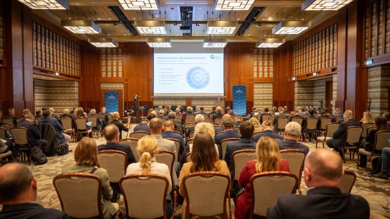 widok na salę konferencyjną z publicznością, scenę, mównicę i ekran z prezentacją