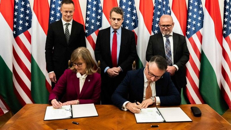Podpisanie amerykańsko-węgierskiej umowy ws. importu LNG. Ministrowie i przedstawiciele biznesu na tle amerykańskich i węgierskich flag.