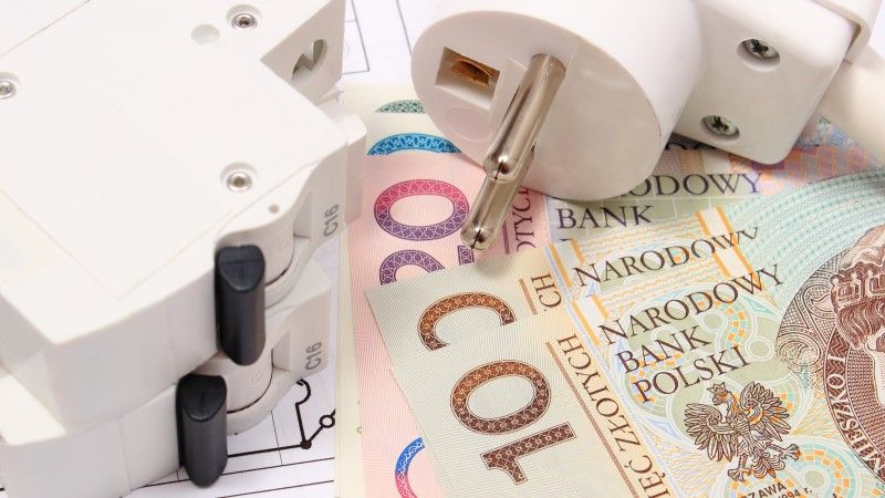 Wtyczka elektryczna leżąca na polskich banknotach.