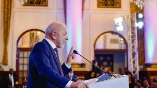 prezydent stoi za mównicą i przemawia do mikrofonu, widoczny z profilu