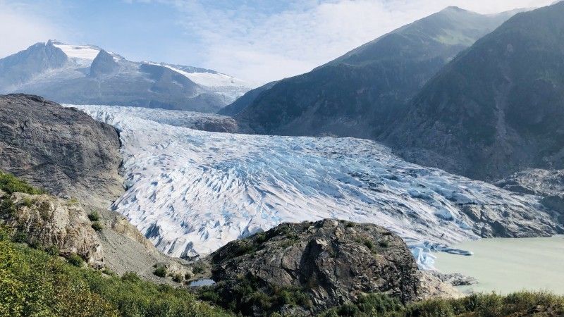 słoneczny dzień, widok na lodowiec górski, lodu jest niewiele, widać zieloną roślinność