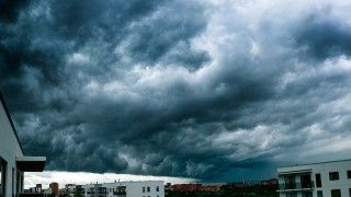 Chmury burzowe zbierające się nad współczesnym osiedlem.