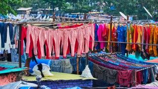 Szeregi kolorowych ubrań wiszących na rozłożonych sznurach.