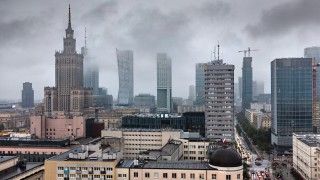 Panorama Warszawy z Pałacem Kultury w chmurach i dymie.