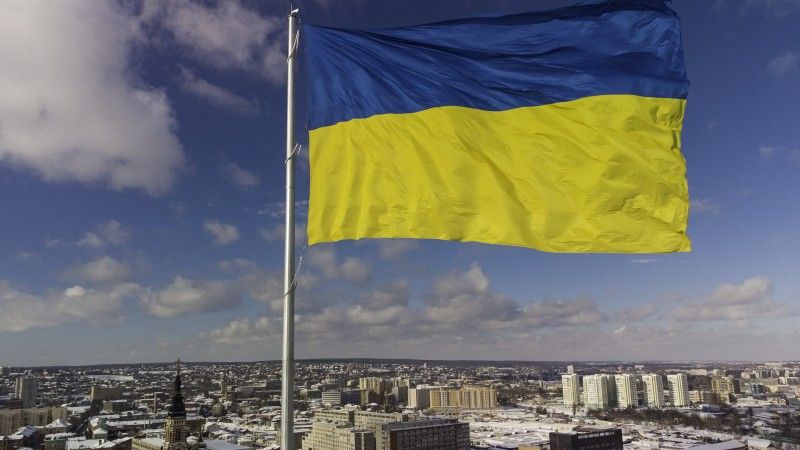 flaga Ukrainy powiewa nad miastem pokrytym śniegiem w słoneczny dzień