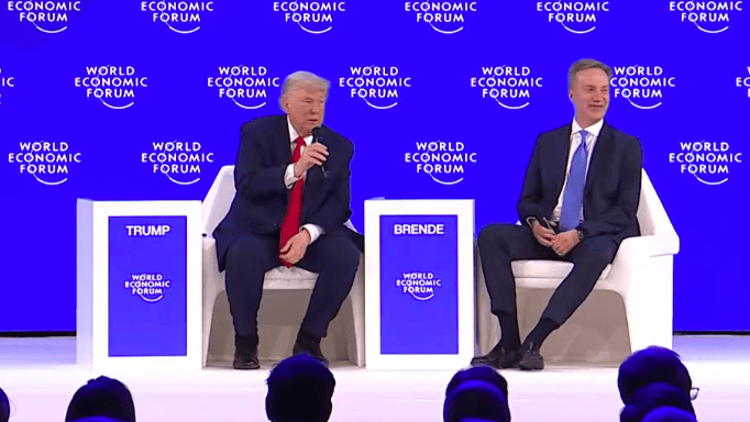 mężczyźni siedzą na krzesłach na scenie, w rękach mają mikrofony