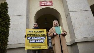 Dwoje działaczy Greenpeace Polska stoją przed Najwyższą Izbą Kontroli z bannerem: Nie dajmy wpuścić się w gazową pułapkę