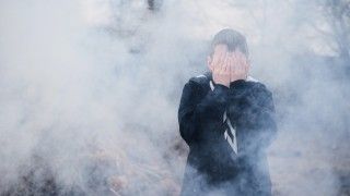 chłopiec stoi w gęstym dymie zakrywa twarz