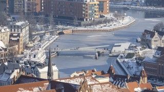 Widok na rzekę Motławę w Gdańsku i okalające ją budynki zimą, w śniegu.