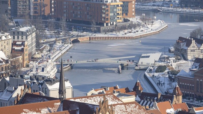 Widok na rzekę Motławę w Gdańsku i okalające ją budynki zimą, w śniegu.