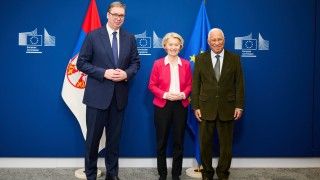 politycy stoją na tle ścianki UE i na tle flag Serbii i UE