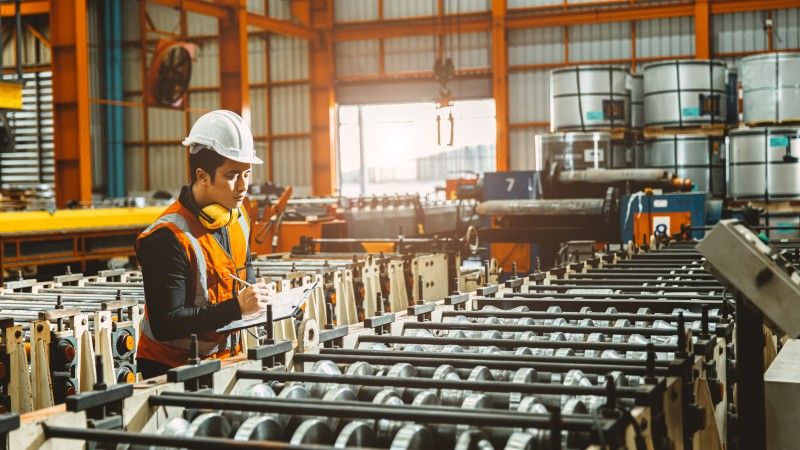 młody inżynier robi kontrolę na produkcji części metalowych