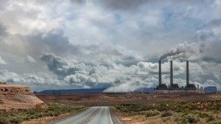 Asfaltowa droga w USA i dym unoszący się z elektrowni węglowej.