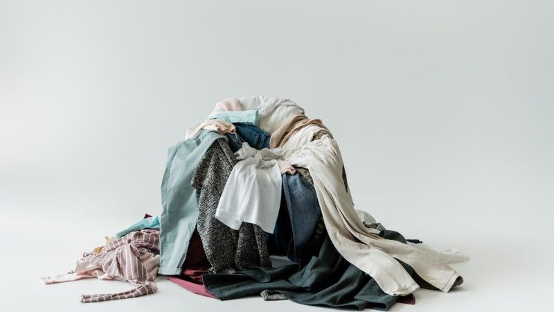 Różnokolorowe ubrania zebrane razem w kupę na fotelu.