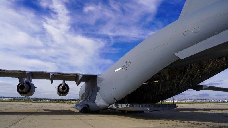 ogromny szary samolot stoi na płycie lotniska z otwartym lukiem bagażowym