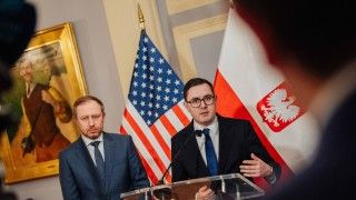 Minister energii Miłoszy Motyka i wiceminister Wojciech Wrochna na briefingu prasowym w Waszyngtonie. W tle polska i amerykańska flaga.