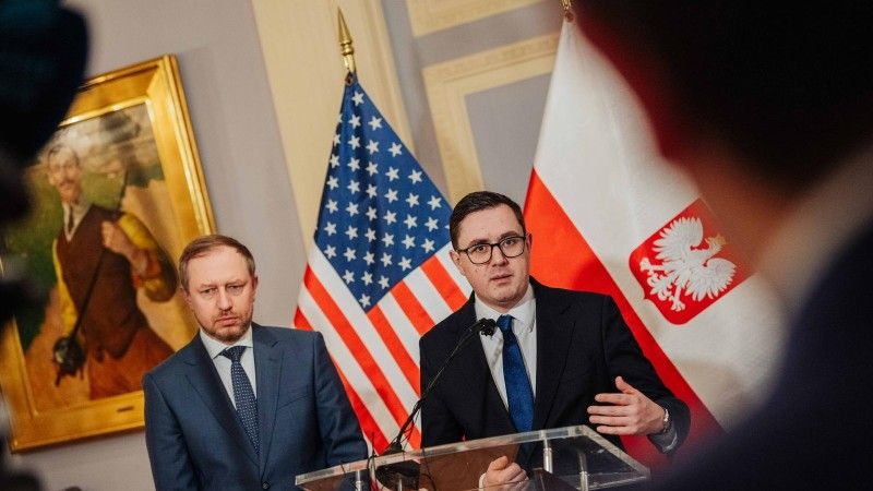 Minister energii Miłoszy Motyka i wiceminister Wojciech Wrochna na briefingu prasowym w Waszyngtonie. W tle polska i amerykańska flaga.