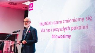 Prezes przemawia zza mównicy na tle prezentacji