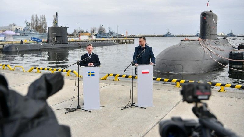 Wicepremier, Minister Obrony Narodowej Władysław Kosiniak-Kamysz i Minister Obrony Szwecji Pål Jonson przemawiają w Porcie Wojennym w Gdyni, 12 marca 2026 roku. Na drugim planie okręty podwodne: ORP „Orzeł” i HMS „Uppland”.