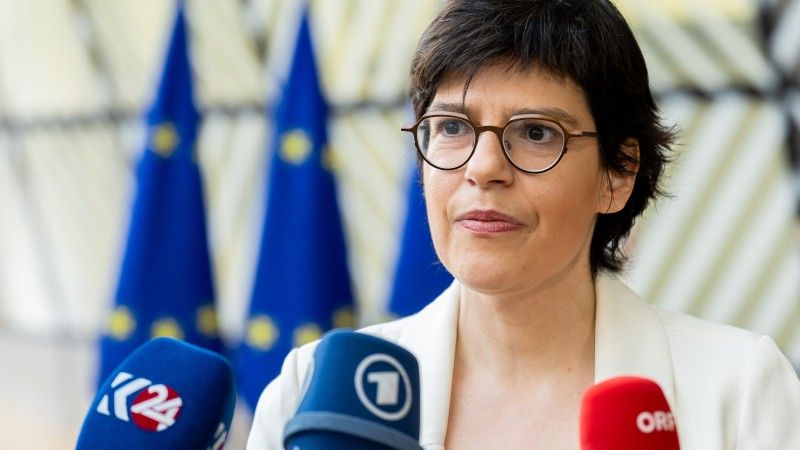 Tinne Van der Straeten podczas wywiadu na tle flag Unii Europejskiej