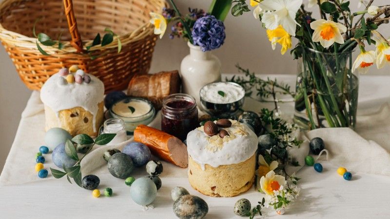 stół zastawiony wielkanocnym jedzeniem, z koszyczkiem, żonkilami i jajkami