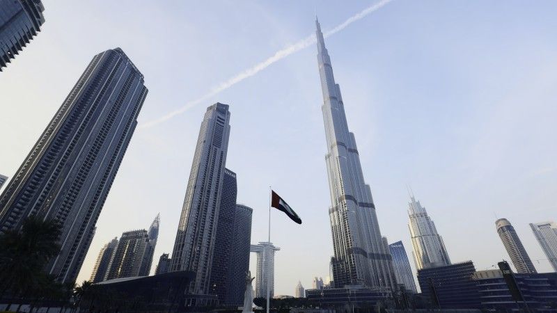 Wieżowce w Dubaju, w tym słynny Burdż Chalifa i flaga ZEA po środku.