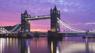 Oświetlony most zwodzony w Londynie Tower Bridge o zachodzie słońca.