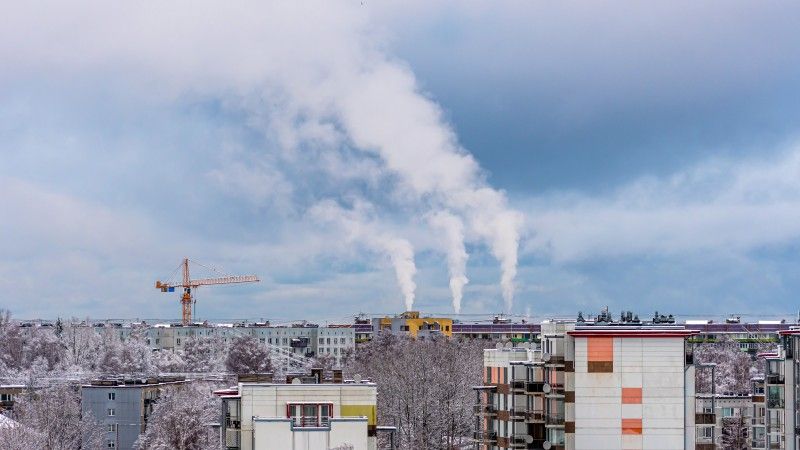 Dym z kominów unoszący się nad blokami zimą.