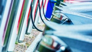 Samochody elektryczne ustawione w szeregu w trakcie ładowania.