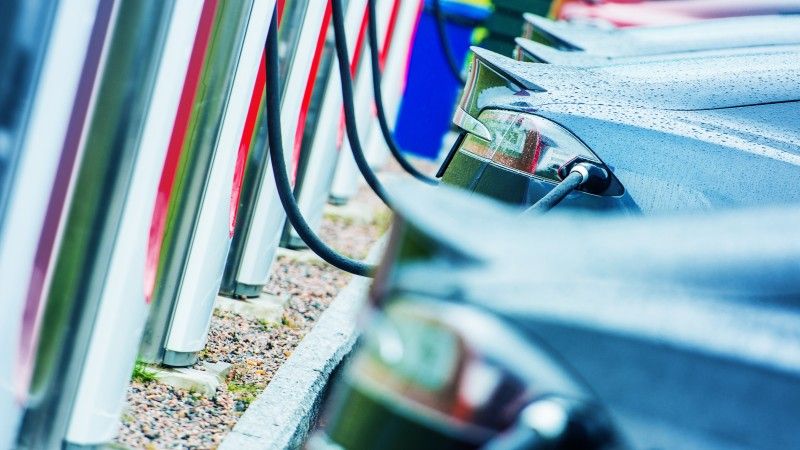 Samochody elektryczne ustawione w szeregu w trakcie ładowania.
