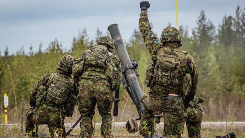Estonian soldiers in camouflage operate a mortar during Exercise Spring Storm 26 in a forest training area.