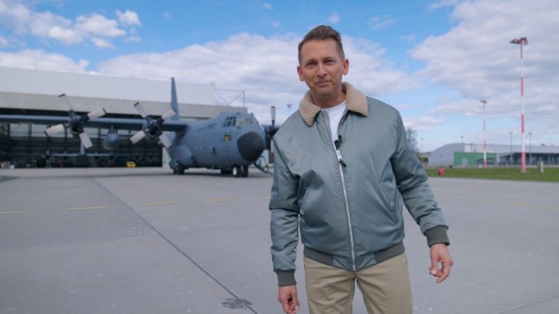 Michał Stela, redaktor Defence24, w 33. Bazie Lotnictwa Transportowego w Powidzu. W tle średni samolot transportowy C-130 Hercules należący do Sił Powietrznych RP.