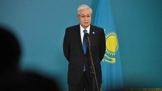 prezydent mówi do mikrofonu na tle flagi Kazachstanu