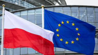 Flaga Polski i Unii Europejskiej na tle szklanego budynku
