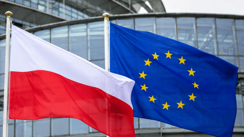 Flaga Polski i Unii Europejskiej na tle szklanego budynku