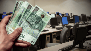 Sala komputerowa i polskie banknoty w dłoni.