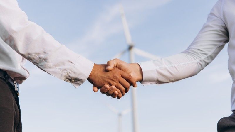 business-deal-handshake-on-wind-farm-background-2026-03-20-04-02-27-utc