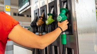 osoba sięga po pistolet do tankowania na stacji benzynowej